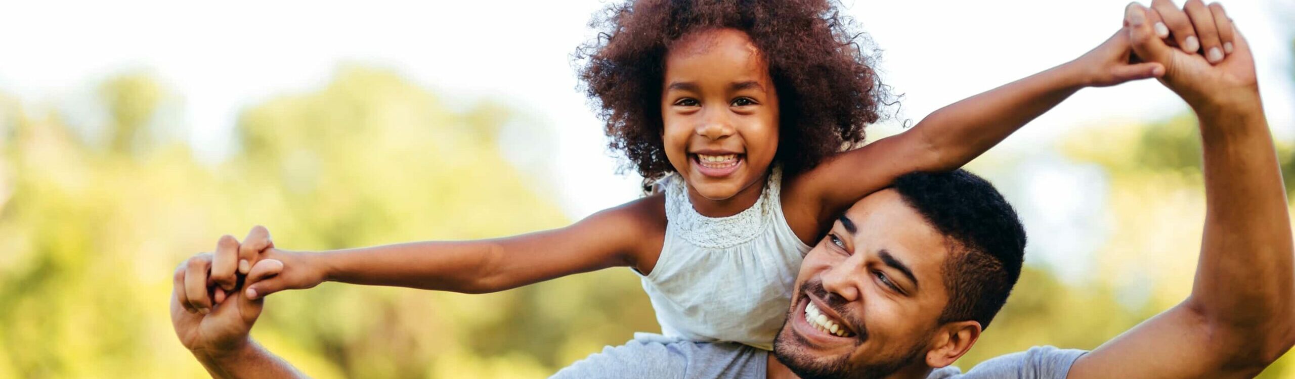 Daughter on Father's shoulders smiling