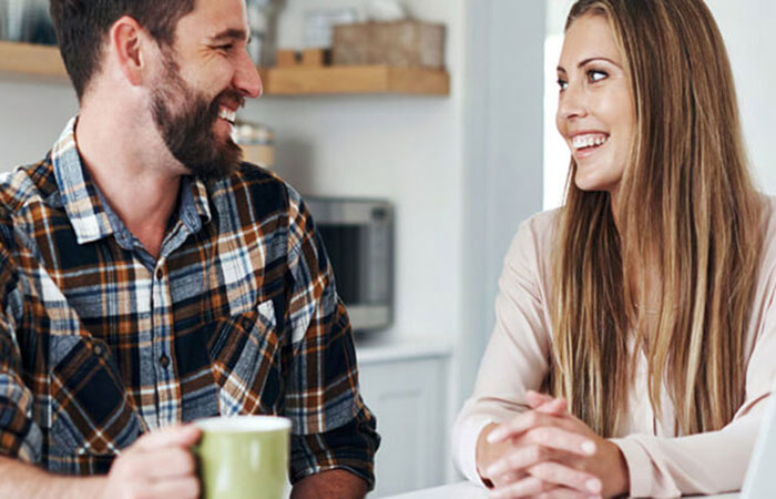 A male and female mobile mortgage manager customer smiling at one another in a kitchen