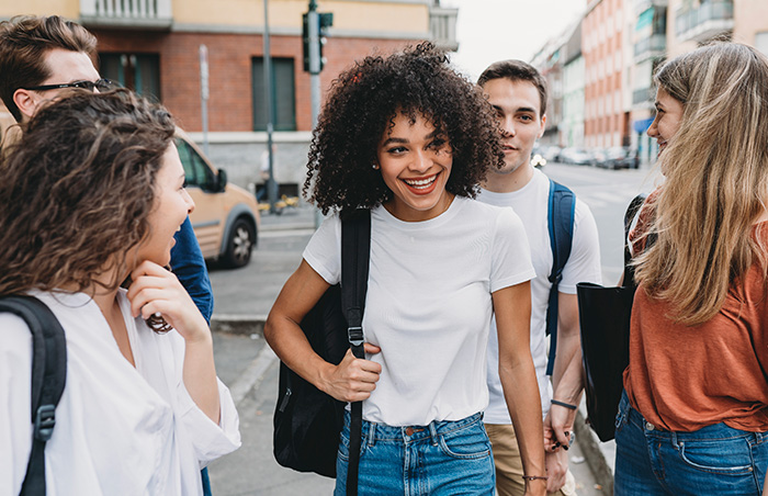 Young group of friends walking down street smiling and laughing