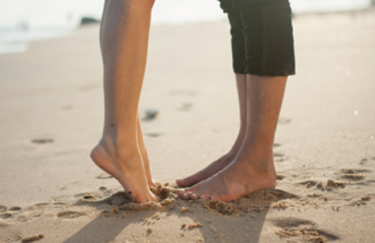 Regular savings account, feet standing on sandy beach near seashore line