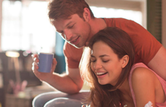 Insurance, home, woman smiling with a man holding a blue cup