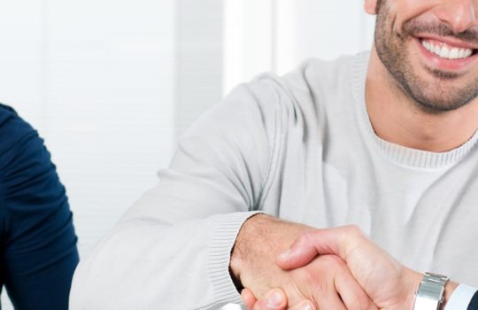 Insurance, mortgage protection, man wearing a grey jumper, smiling and shaking hands