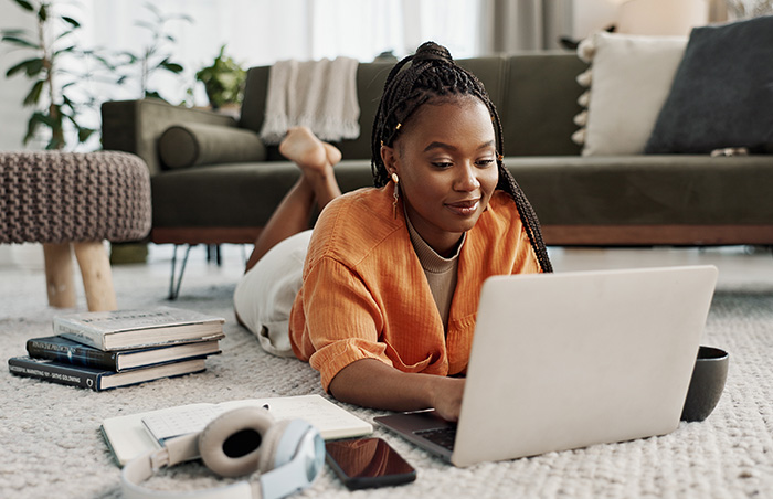 Woman laying on carpet using laptop