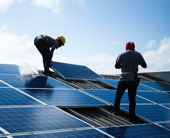 Two men installing solar panels on a roof.